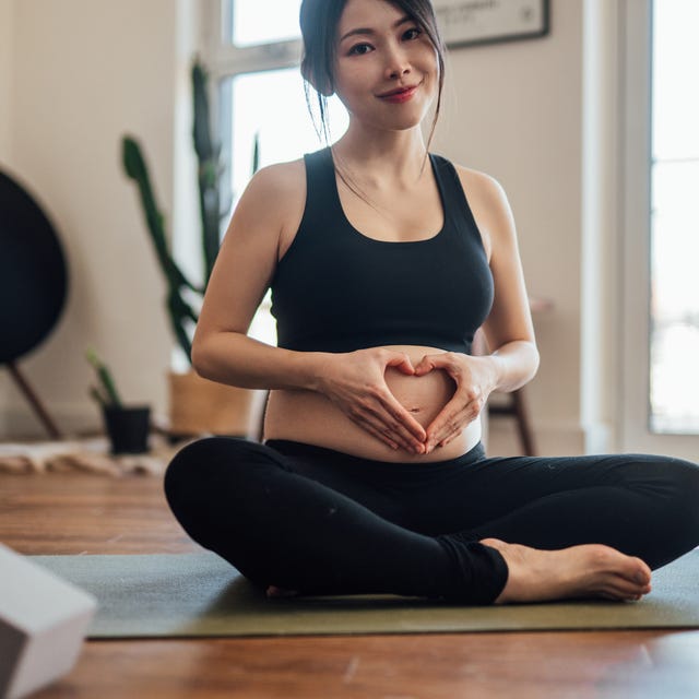 pregnant woman putting her hands and making heart shape on her belly