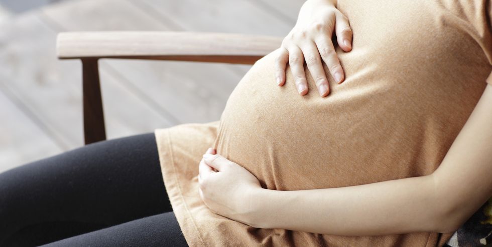 pregnant woman touching abdomen sitting chair