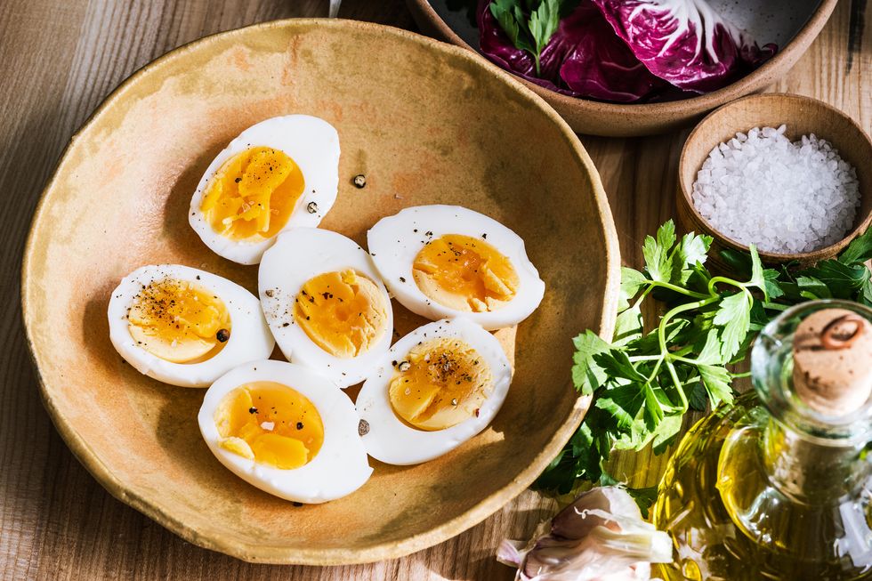 preparing healthy food with boiled eggs ingredients, fresh vegetables, herbs