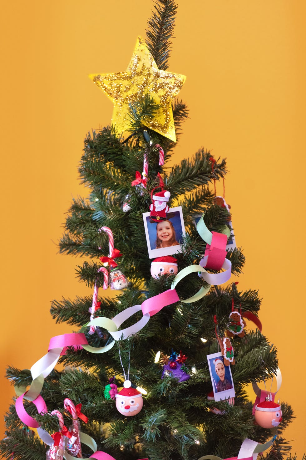 a christmas tree with polaroid photos of people on it