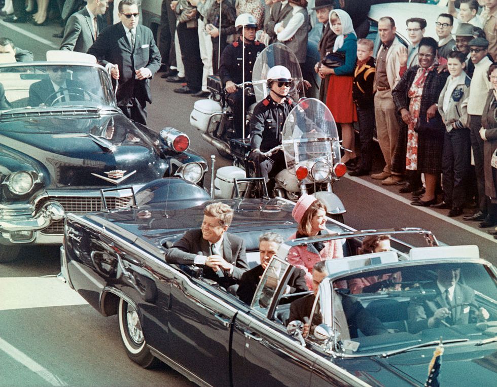 john f kennedy, jackie kennedy, john connally, and other passengers ride in a car together as people line the street to watch