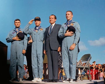 astronauts from the apollo 13 flight crew saluting and holding their caps to their chest as they stand next to president richard nixon