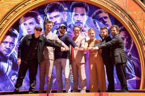 producer kevin feige, chris hemsworth, chris evans, robert downey jr, scarlett johansson, mark ruffalo, and jeremy renner stand on a stage and each have on fist forward while posing for a picture
