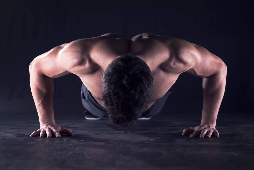young muscular man doing push ups on the gym floor he is looking down