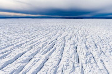 pressure ridges and crevasse scar the surface of a glacier on the greenland ice sheet