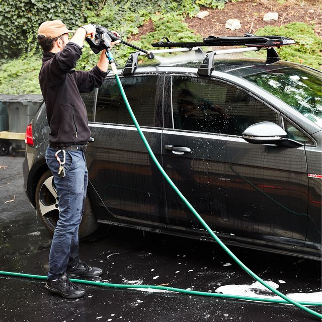 a person using a pressure washer to clean the roof of their car
