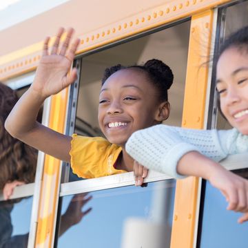 preteen schoolgirls waving from school bus