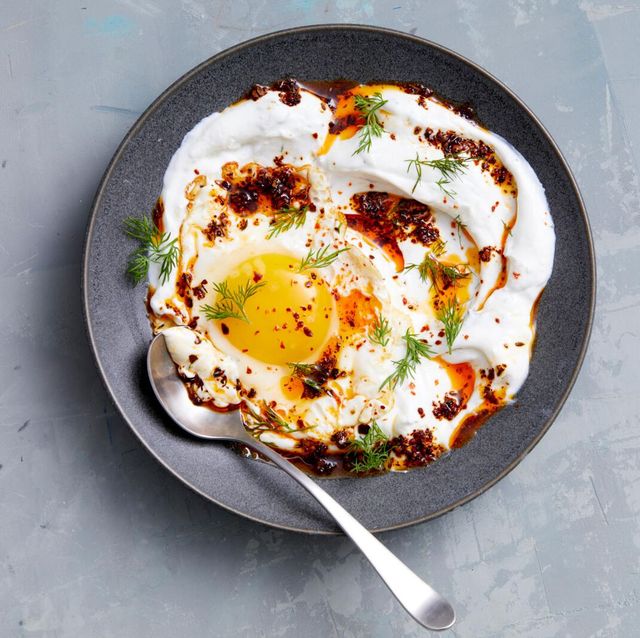 turkish eggs with yogurt in a dark gray bowl on a light gray background