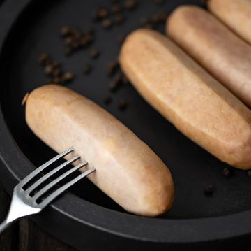 prick sausage on fork and sausages on plate. eating sausage. chicken sausages. boiled sausage in natural casing. grilled veal sausages. top view. copy space. close up