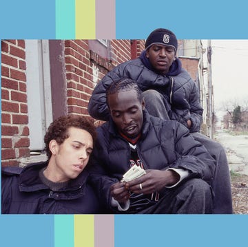 three men, including omar little, looking at money, sitting on a step in the street