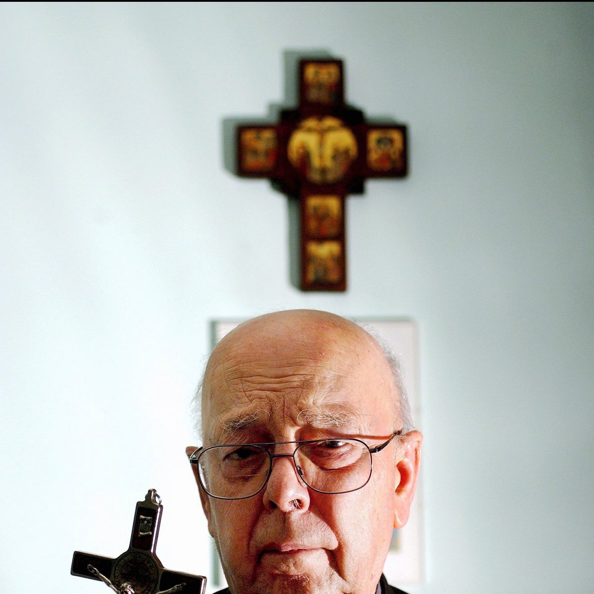 father gabriele amorth holding a crucifix in front of religious articles on a wall