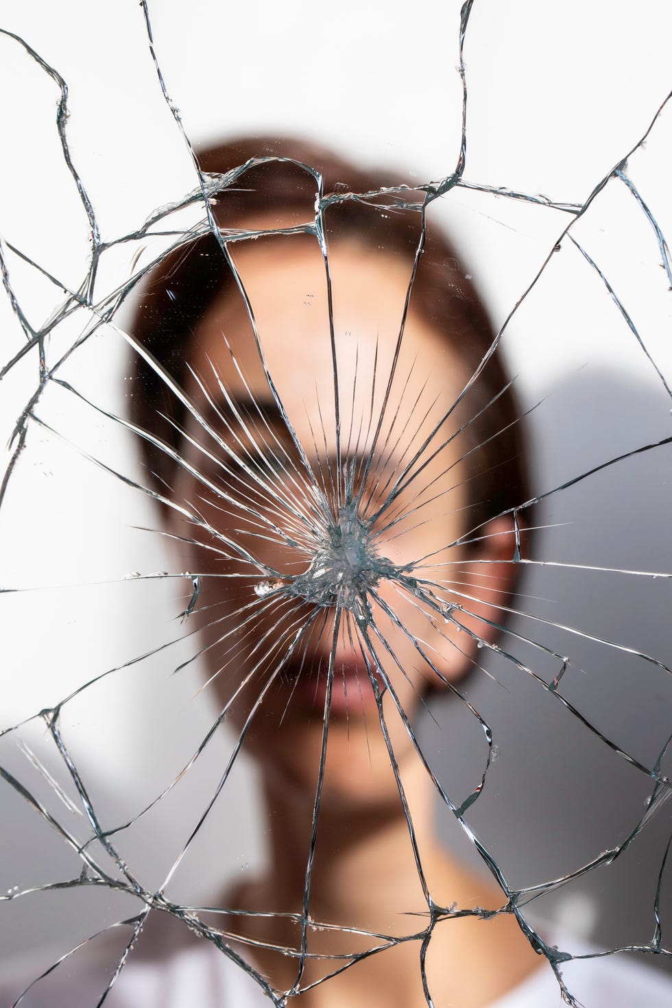 a woman staring in a shattered glass mirror