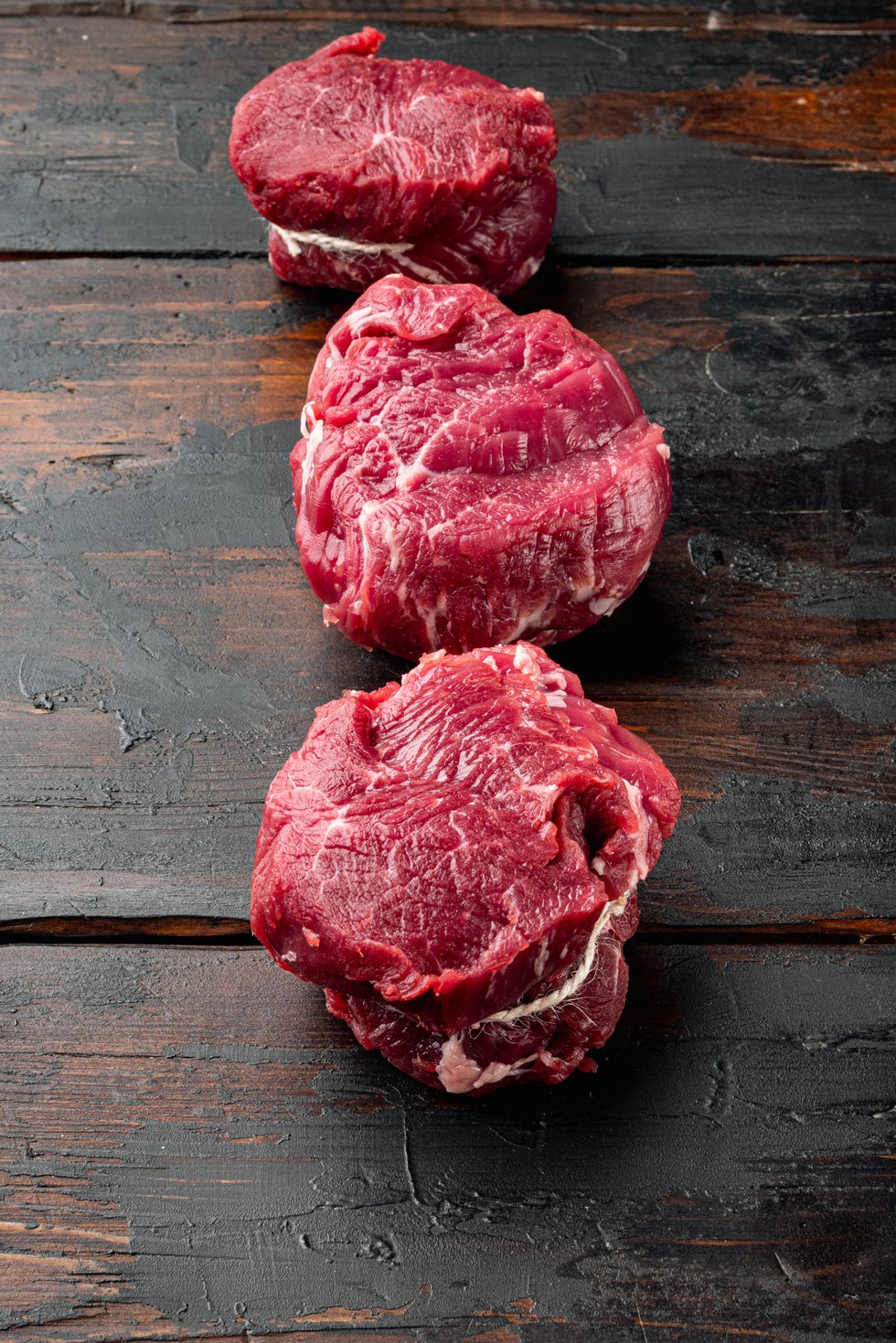 prime raw fillet mignon tenderloin steaks, on old dark  wooden table background