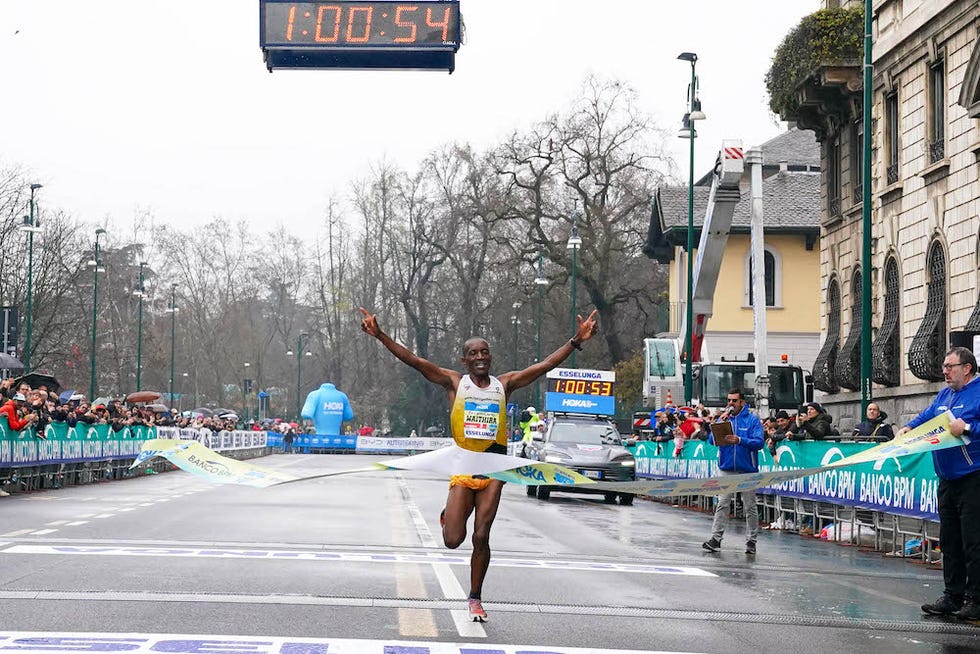 athlete crossing the finish line of a marathon with a stopwatch recording the time
