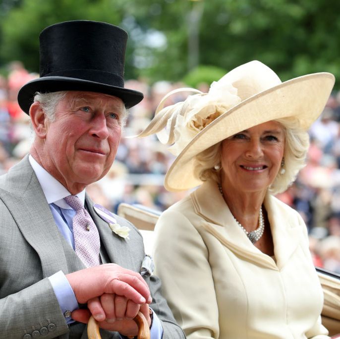 charles and camilla in a carriage at ascot smiling at the crowd