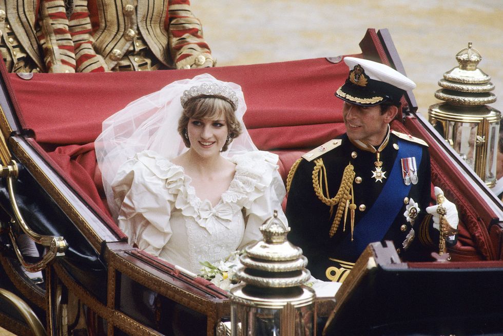 princess diana wearing a white wedding dress, and prince charles wearing a military uniform, sitting in a gold and red open carriage and smiling