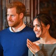 prince harry and meghan markle smiling at something out of frame