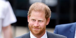 prince harry smiles in a suit as he walks into court