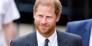 prince harry smiles in a suit as he walks into court