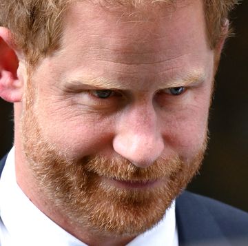 a close up of prince harry's face, looking off camera and appearing thoughtful, while wearing a blue suit