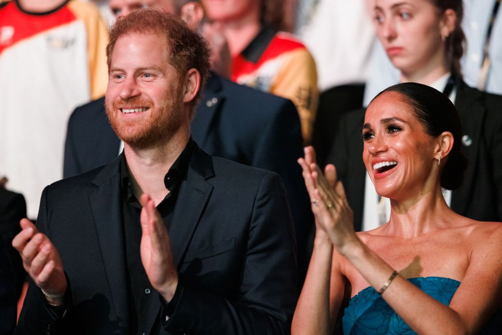 prince harry and meghan markle smiling and clapping at invictus games