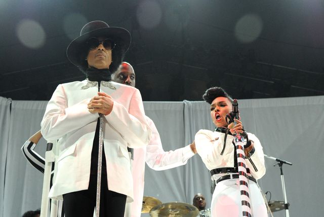 prince and janelle monae, both wearing white outfits, stand on a stage in front of a band while monae sings into a microphone