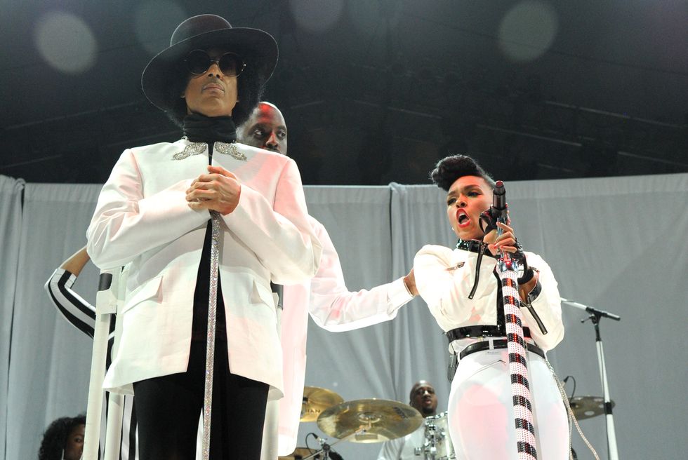 prince and janelle monae, both wearing white outfits, stand on a stage in front of a band while monae sings into a microphone