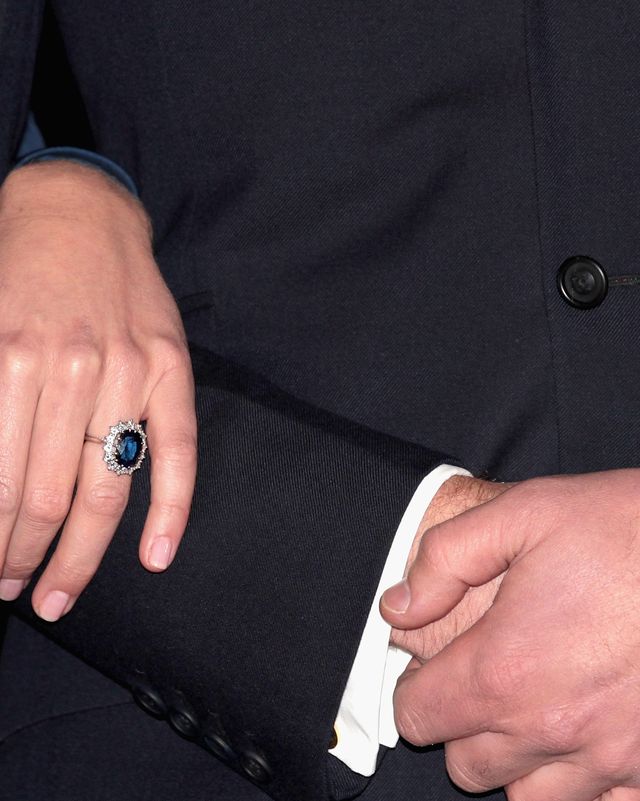 a large sapphire ring surrounded by diamonds is worn on a hand