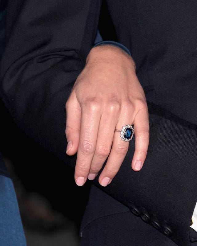 a large sapphire ring surrounded by diamonds is worn on a hand