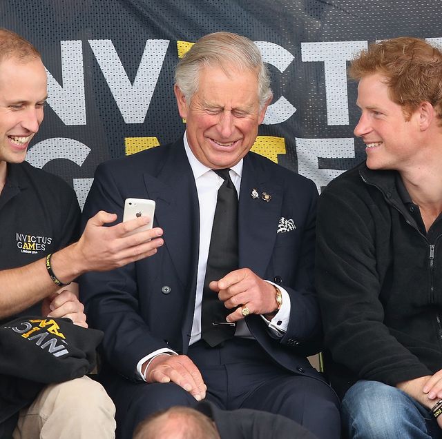 prins harry, prins william en koning charles bij de invictus games kijkend op een telefoon en lachend