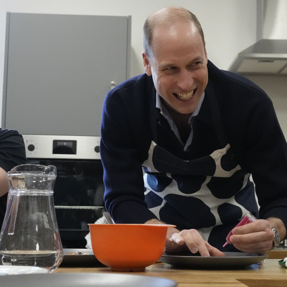 prince william, prince of wales smiles as he looks up while decorating biscuits during his visit to a youth centre