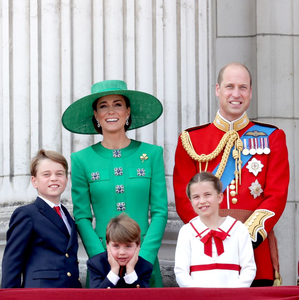 prince george, prince louis, princess kate, princess charlotte, and prince william stand on a balcony and smile