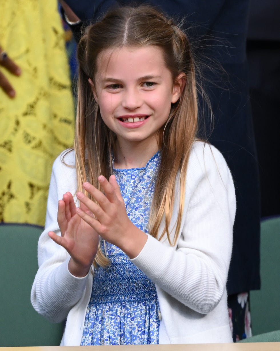 Princess Charlotte of Wales attends a Wimbledon tennis match on July 16, 2023, in London princess charlotte claps her hands and smiles as she stands, she wears a white long sleeve sweater and blue floral dress