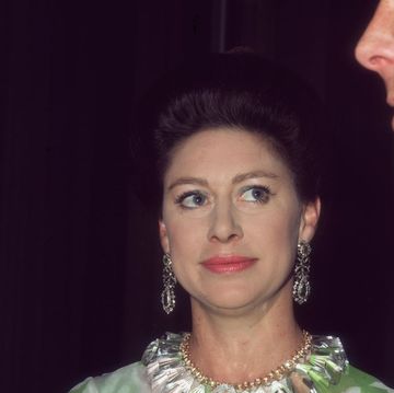 princess margaret looks to the right, she wears large dangling earrings, a matching large necklace and a green and white top