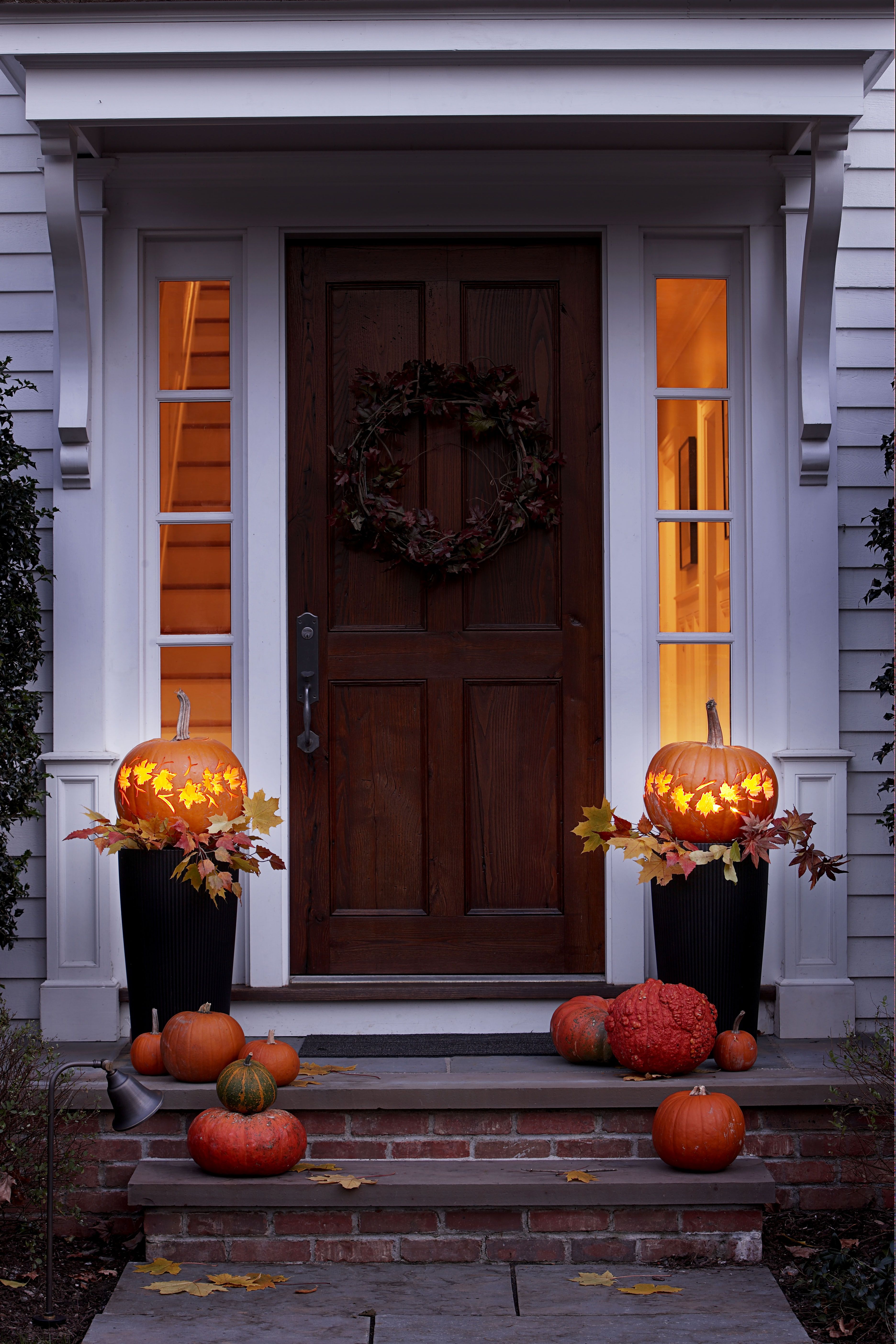 Front path, steps and open front door with fall leaves and jack-o-lantern  Stock Photo