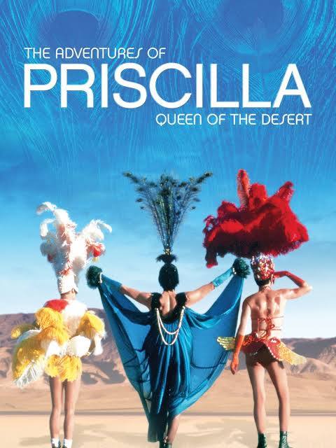 three individuals in elaborate costumes posing in a desert setting