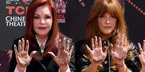 priscilla presley and riley keough look at the camera with their concrete covered palms out