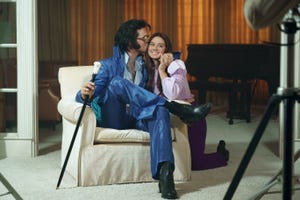 elvis presley sitting in a chair and kissing a smiling priscilla presley in a scene from the film priscilla