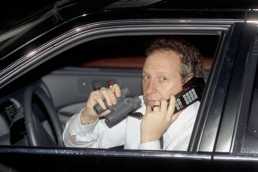 anthony pellicano holding a phone and binoculars inside his car