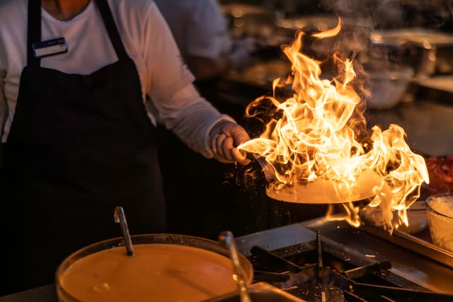 pro chef flambeing in the kitchen in a pan on a gas fired stove