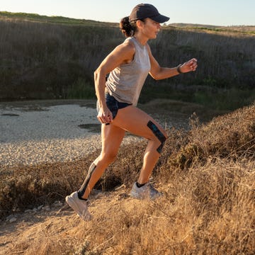 woman running uphill on a trail with athletic attire and kinesiology tape on her legs woman running uphill on a trail with athletic attire and kinesiology tape on her legs
