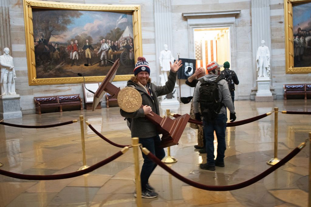 a pro trump protester carries the lectern of us speaker of the house nancy pelosi through the roturnda of the us capitol building after a pro trump mob stormed the building on january 06, 2021 in washington, dc congress held a joint session today to ratify president elect joe biden's 306 232 electoral college win over president donald trump a group of republican senators said they would reject the electoral college votes of several states unless congress appointed a commission to audit the election results