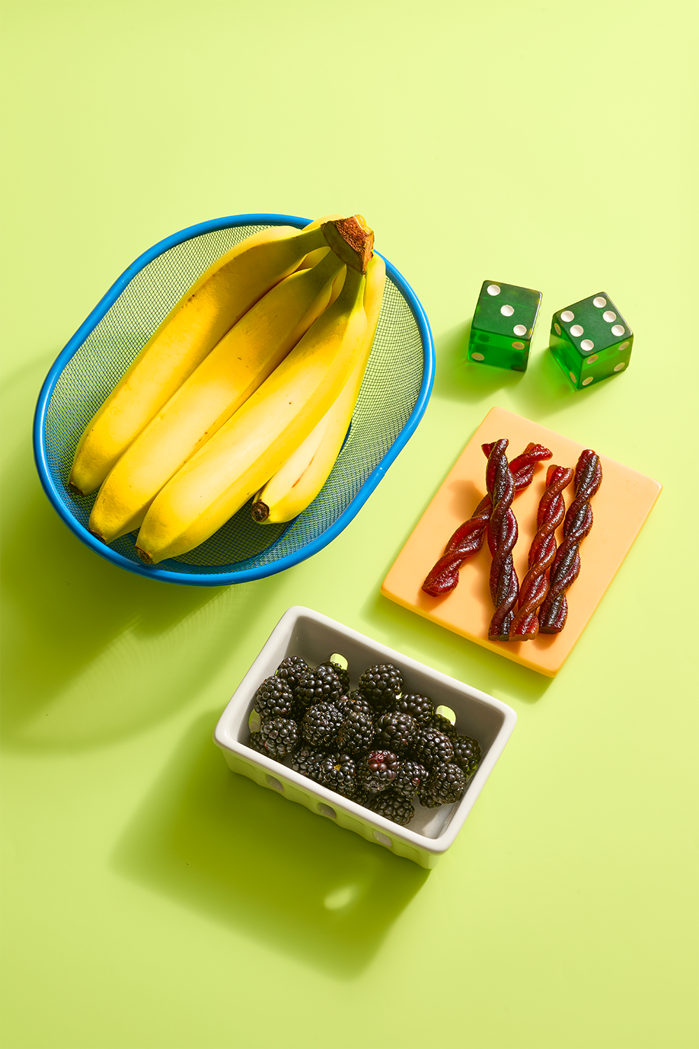 bananas, blackberries and dried fruit snacks with green dice on a table