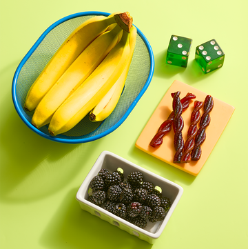 Bananas, blackberries and dried fruit snacks with green dice on a table bananas, blackberries and dried fruit snacks with green dice on a table