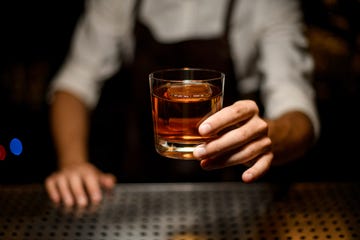 professional bartender serving a cocktail in the glass with one big ice cube