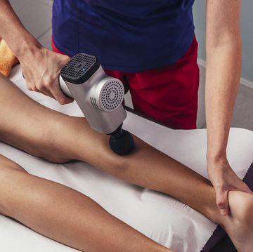 fysiotherapeut behandelt iemand met een massage gun