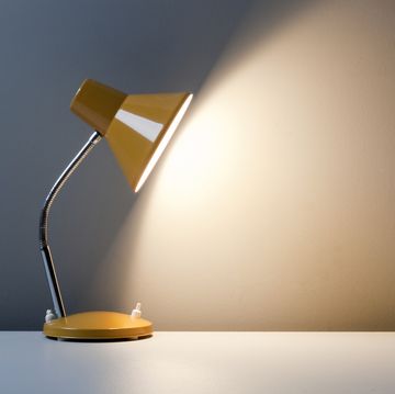 profile of yellow desk lamp, turned on on white table