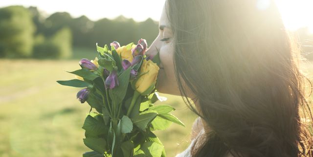 Profile of young woman smelling bunch of flower at sunset
