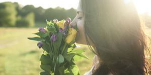 Profile of young woman smelling bunch of flower at sunset
