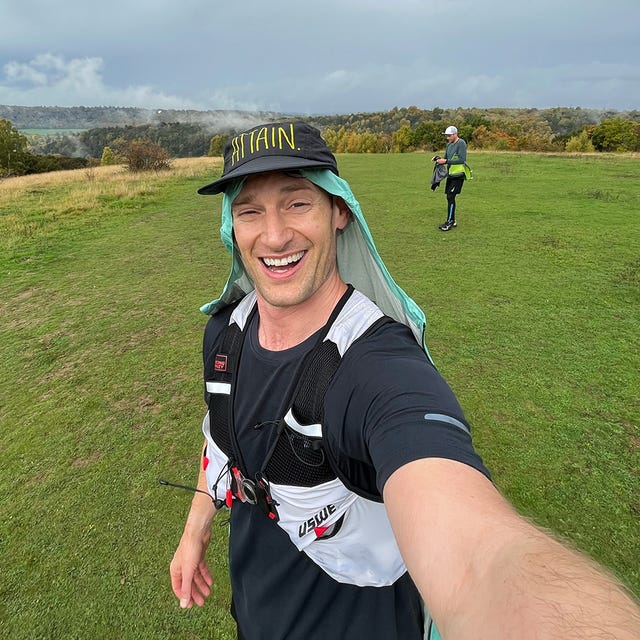 a man wearing a hat and running on a grass field